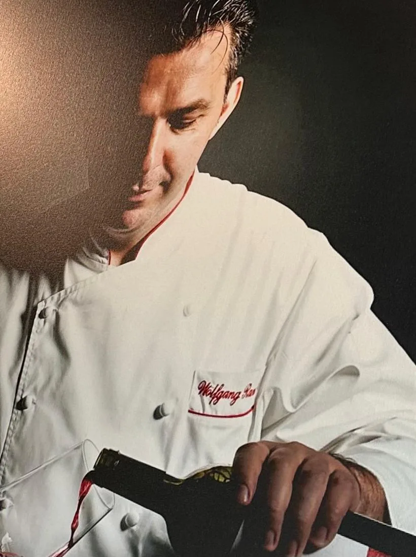 Masterchef Wolfgang Ranner in his whites, pouring a glass of wine
